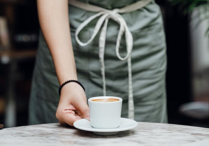 crop waitress serving cup of coffee